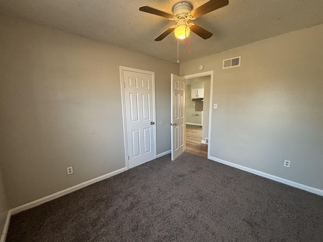 unfurnished bedroom featuring baseboards, dark colored carpet, and ceiling fan