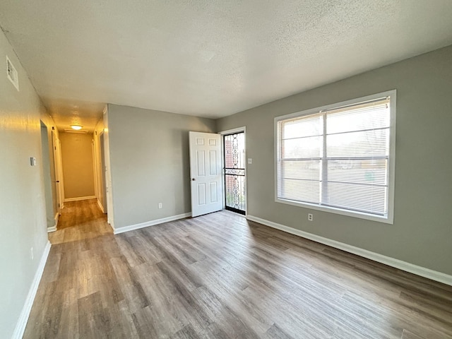empty room featuring wood finished floors, baseboards, and a textured ceiling