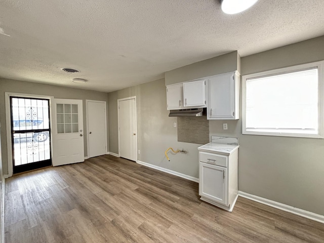 kitchen with a textured ceiling, white cabinetry, light wood-type flooring, light countertops, and baseboards