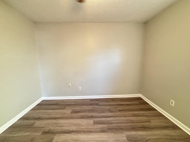 spare room with dark wood finished floors, baseboards, and a textured ceiling
