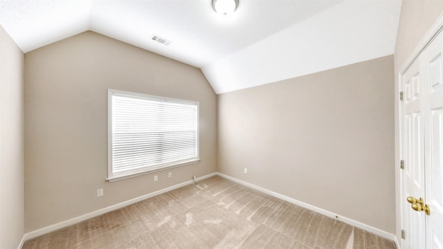 unfurnished room with lofted ceiling, light colored carpet, and baseboards