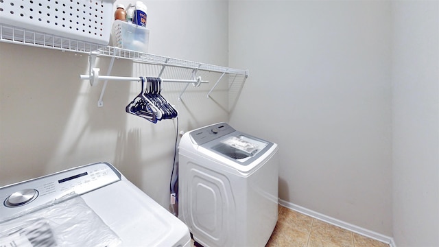 clothes washing area featuring separate washer and dryer, baseboards, and tile patterned floors