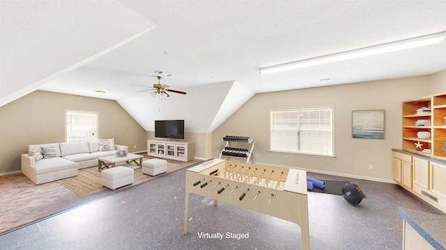 game room featuring a ceiling fan, baseboards, vaulted ceiling, and a textured ceiling