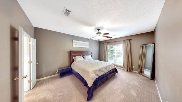 bedroom with light carpet, baseboards, a textured ceiling, and ceiling fan