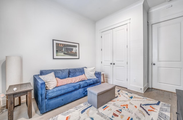 living area featuring ornamental molding, wood finished floors, and baseboards