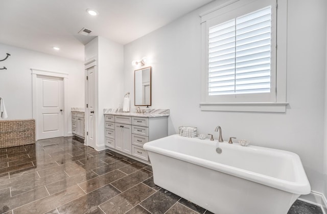 full bathroom featuring vanity, a freestanding bath, and recessed lighting
