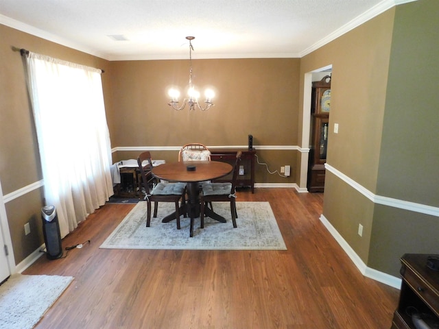 dining area with wood finished floors, a chandelier, crown molding, and baseboards