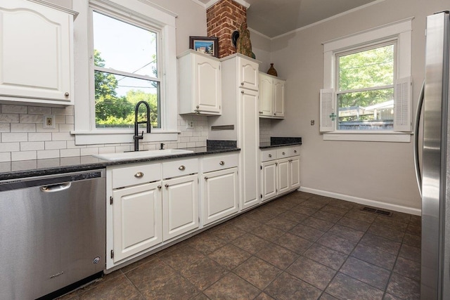 kitchen with appliances with stainless steel finishes, a sink, crown molding, backsplash, and white cabinets