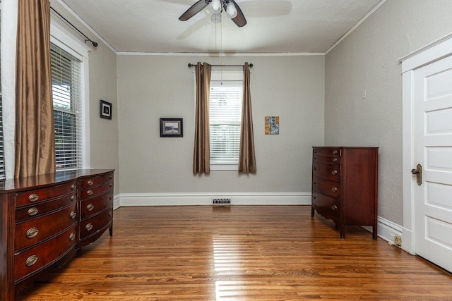 bedroom with wood finished floors, multiple windows, crown molding, and baseboards
