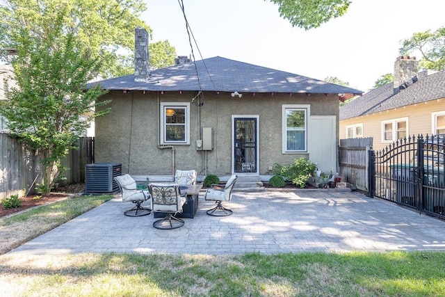 rear view of house with central air condition unit, stucco siding, a fenced backyard, a patio area, and roof with shingles