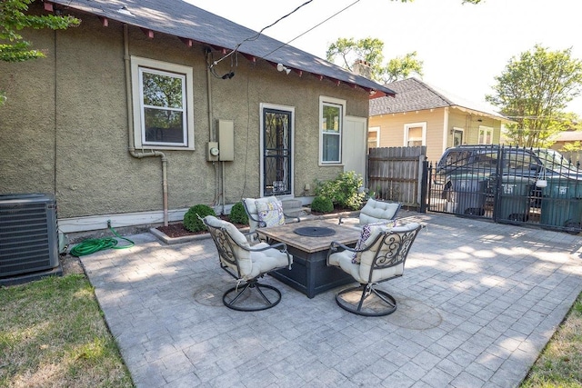 view of patio featuring central AC, fence, and an outdoor fire pit