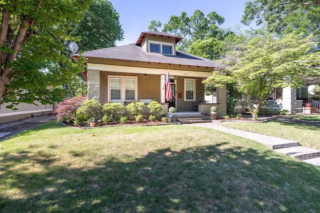 bungalow-style house featuring a porch, a front yard, and stucco siding