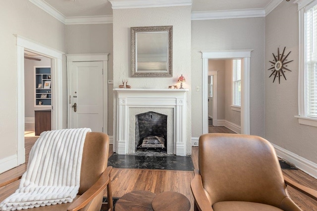 living room with wood finished floors, crown molding, a fireplace, and baseboards