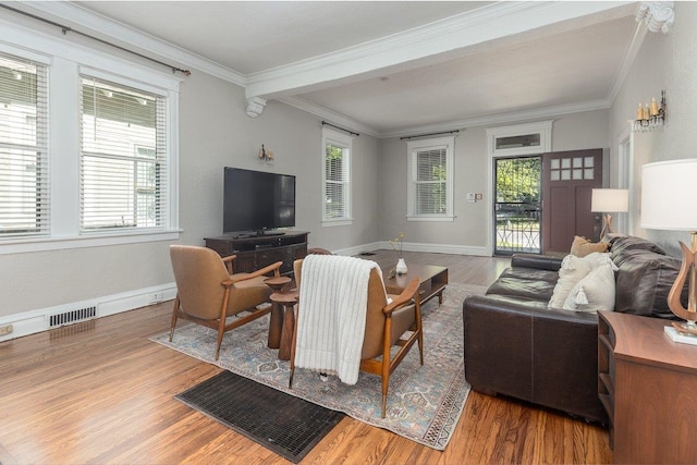living area featuring crown molding, wood finished floors, healthy amount of natural light, and baseboards