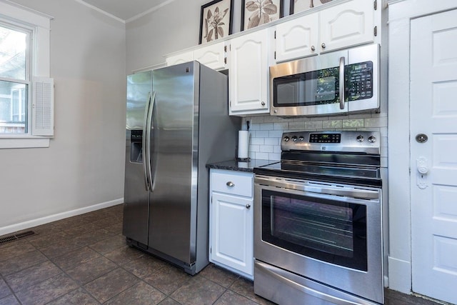 kitchen with appliances with stainless steel finishes, white cabinets, decorative backsplash, baseboards, and dark stone countertops