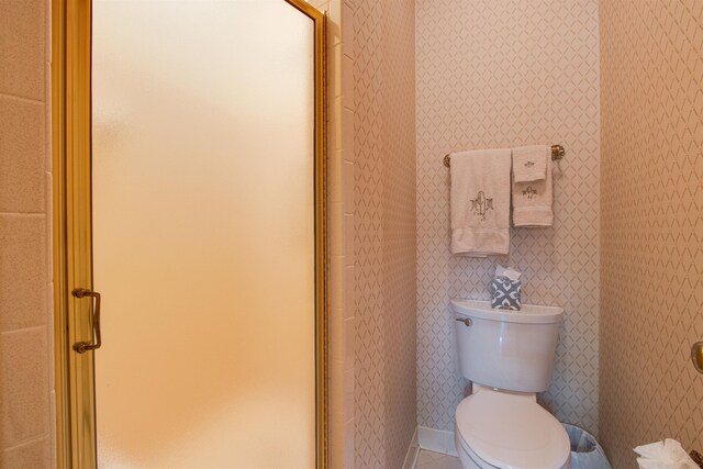 bathroom featuring tile patterned floors, toilet, and a shower stall