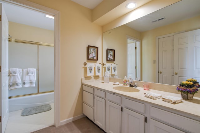 bathroom with vanity, shower / bath combination with glass door, and baseboards