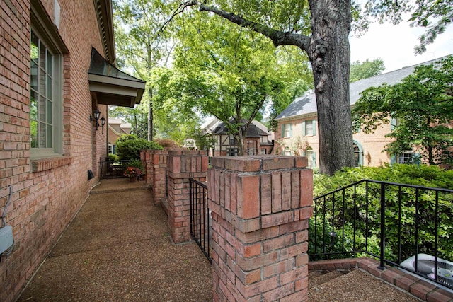 view of side of home with brick siding and fence