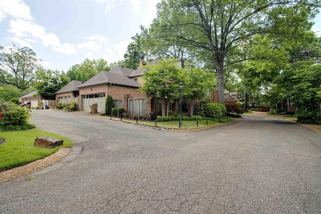 view of front of house featuring an attached garage, fence, brick siding, and driveway