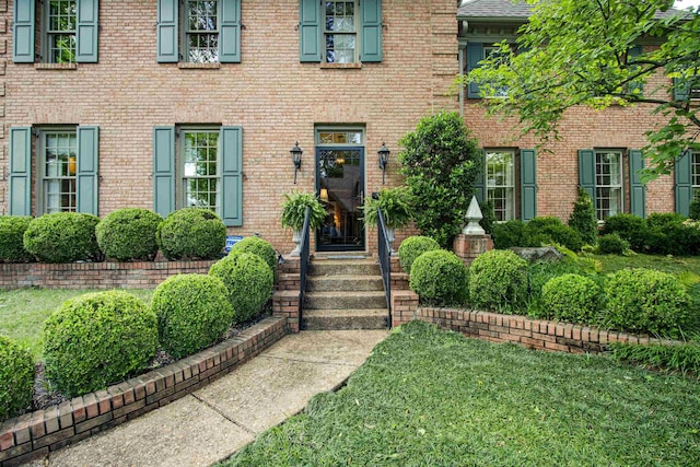 property entrance featuring brick siding and a yard