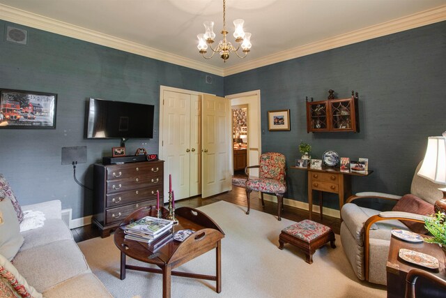 living room with a chandelier, wood finished floors, baseboards, and crown molding