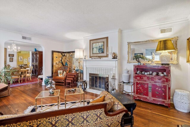 4948 Roane Rd, Memphis, TN 38117 - living area featuring arched walkways, wood finished floors, a textured ceiling, crown molding, and a tile fireplace