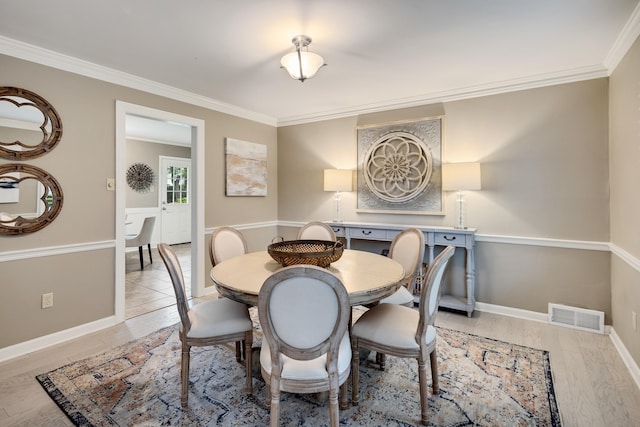 dining area featuring crown molding, light wood-style flooring, and baseboards