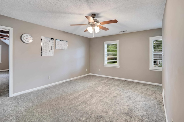 empty room with carpet floors, a ceiling fan, baseboards, and a textured ceiling