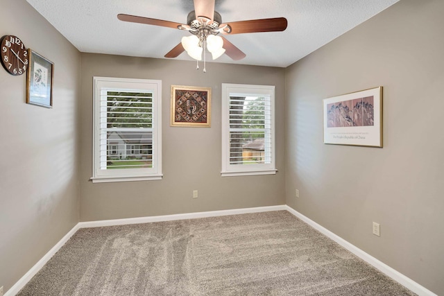 carpeted spare room with ceiling fan, baseboards, and a textured ceiling
