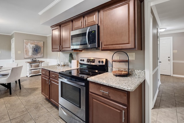 kitchen featuring appliances with stainless steel finishes, light tile patterned flooring, ornamental molding, and light stone countertops