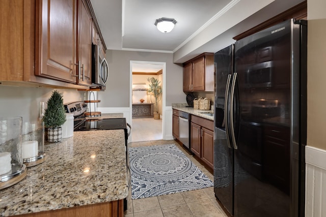 kitchen featuring appliances with stainless steel finishes, light tile patterned flooring, light stone countertops, crown molding, and brown cabinetry
