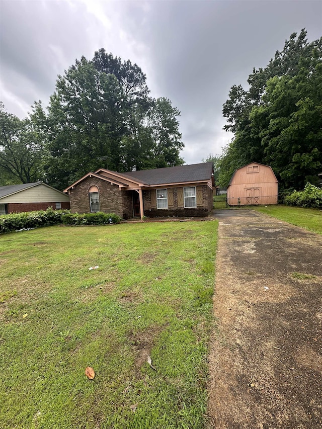 single story home featuring driveway, a front lawn, an outdoor structure, and a barn