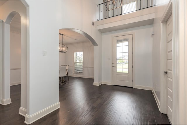entrance foyer with dark wood-style floors, baseboards, and arched walkways