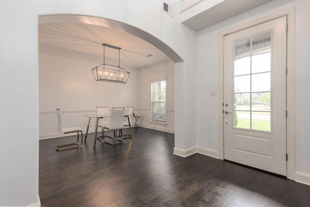 dining area featuring arched walkways, dark wood-style floors, baseboards, ornamental molding, and a chandelier
