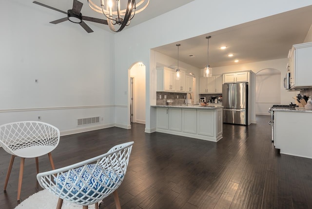 kitchen featuring arched walkways, stainless steel appliances, a peninsula, ceiling fan, and white cabinetry