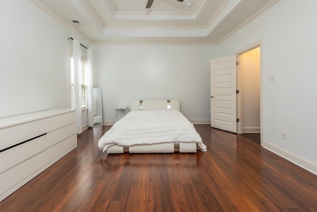 bedroom with dark wood-style floors, a raised ceiling, ornamental molding, baseboards, and a ceiling fan
