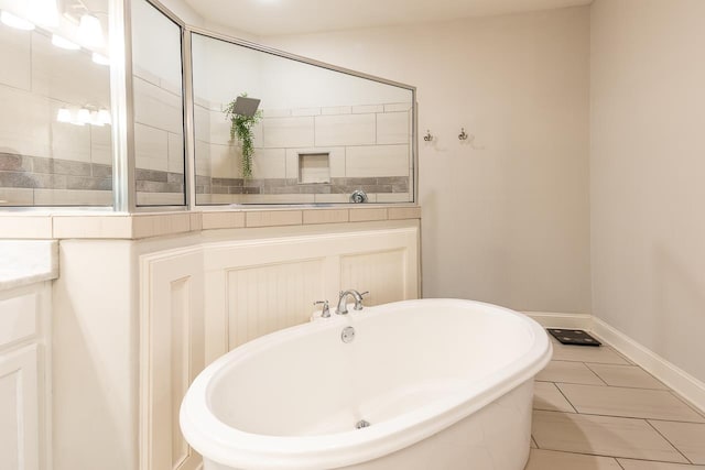 full bath featuring a freestanding tub, baseboards, and tile patterned floors