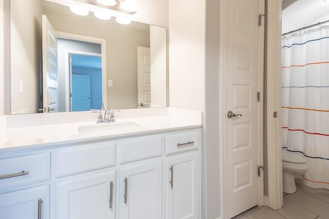 bathroom featuring toilet, vanity, and curtained shower