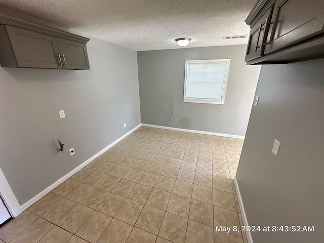 unfurnished dining area featuring light tile patterned floors, a textured ceiling, and baseboards