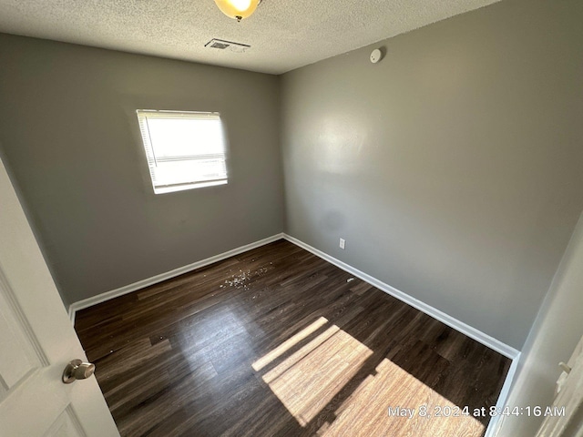 spare room with a textured ceiling, wood finished floors, baseboards, and a smoke detector