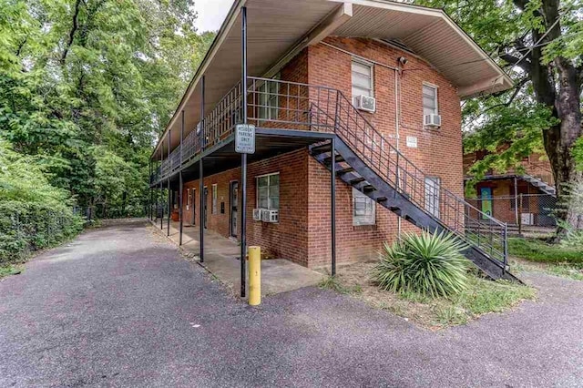 view of home's exterior with brick siding, stairway, and cooling unit