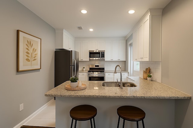 3573 Galloway Ave, Memphis, TN 38122 - kitchen with stainless steel appliances, a peninsula, decorative backsplash, white cabinetry, and recessed lighting