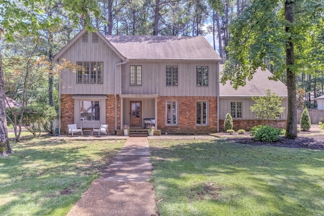 view of front of property featuring brick siding, a front yard, and roof with shingles
