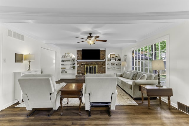 living room featuring ceiling fan, a brick fireplace, dark wood-type flooring, ornamental molding, and built in features