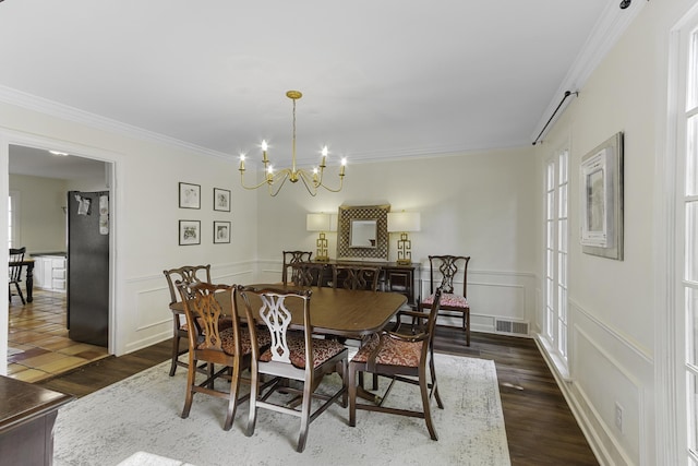 dining space with crown molding, a chandelier, dark wood-style floors, a decorative wall, and a wainscoted wall