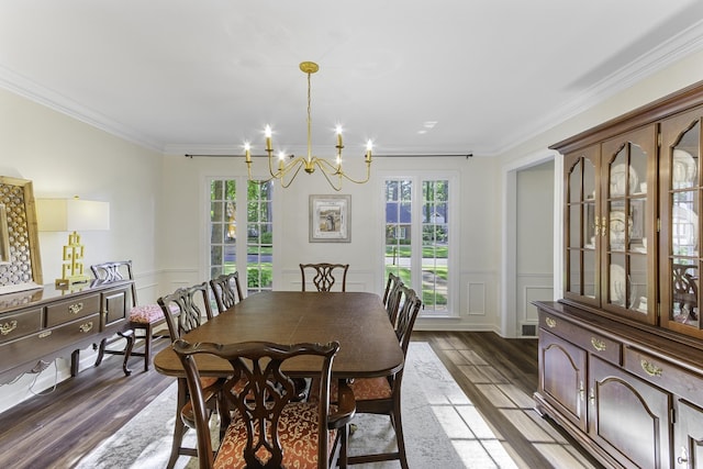 dining area with wood finished floors, healthy amount of natural light, a chandelier, a decorative wall, and crown molding