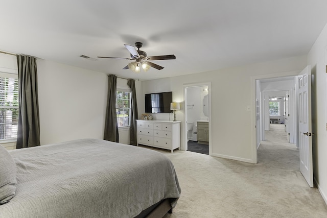 bedroom featuring light colored carpet, multiple windows, baseboards, and a ceiling fan