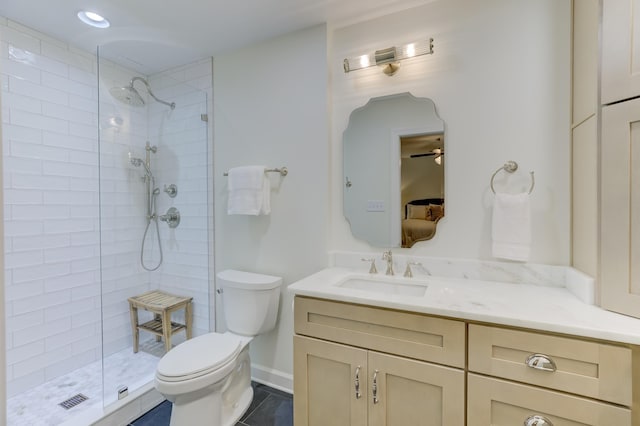bathroom featuring toilet, a tile shower, vanity, tile patterned floors, and ceiling fan