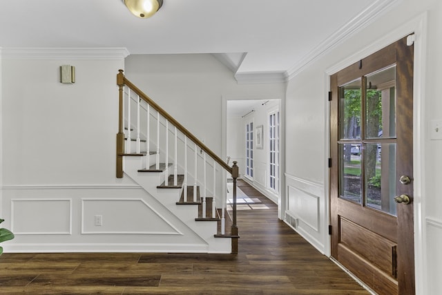 foyer with ornamental molding, a decorative wall, stairway, dark wood-style flooring, and wainscoting