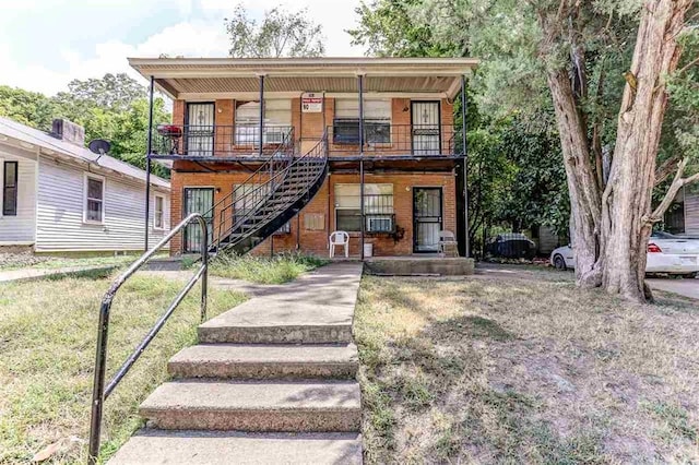 view of front facade featuring stairs, a front yard, covered porch, and brick siding